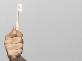 close-up-hand-holding-toothbrush-sos-mau-hálito-ferramenta-avisa-anonimamente