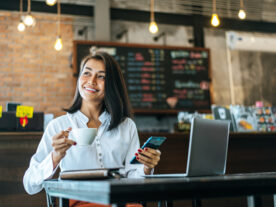 woman-sitting-happily-working-with-smartphone-coffee-shop-notebook-Faturamento-de-franquias-cresce-21-em-Curitiba-Londrina-tambem-regista-aumento-scaled.jpg